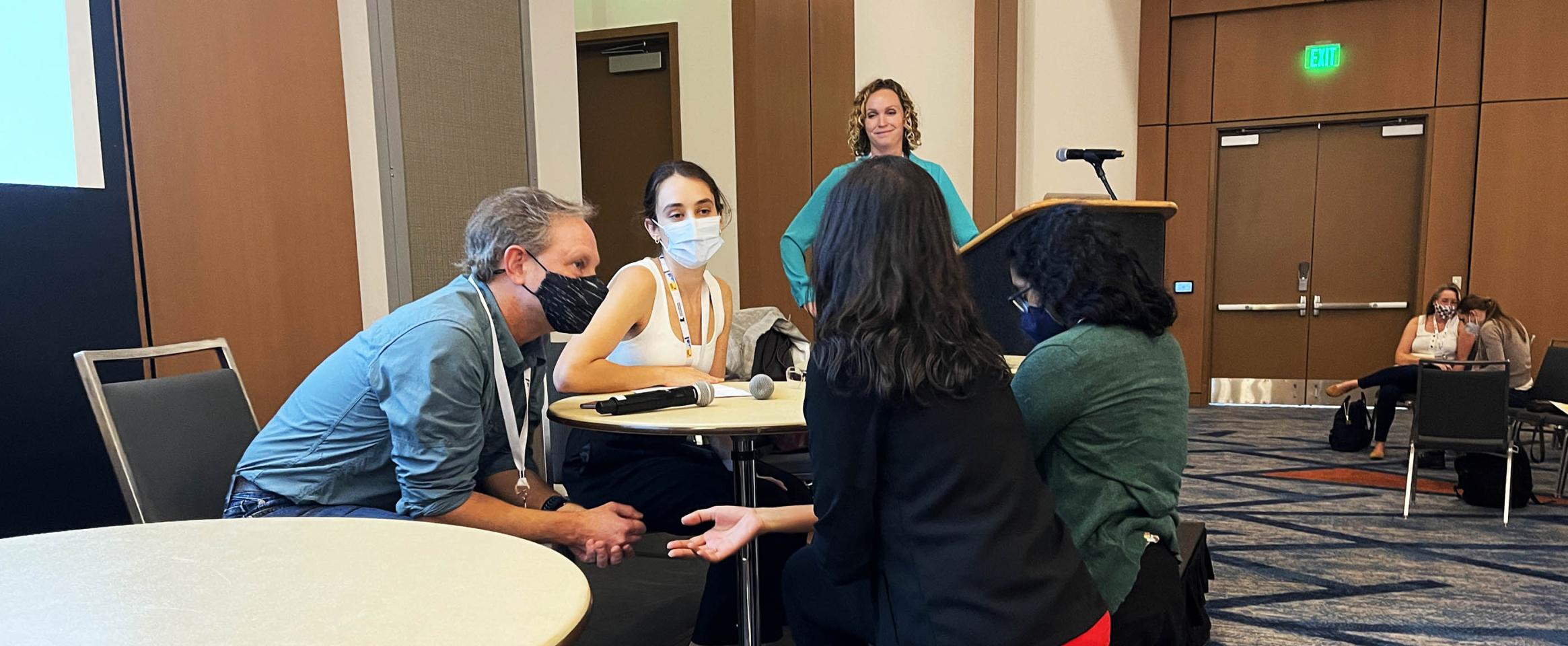 Some attendees lean into the stage to ask the panelists questions during the Interviewing for Narrative Science Stories session at Science Writers 2022, with moderator Katharine Gammon looking on from the background.