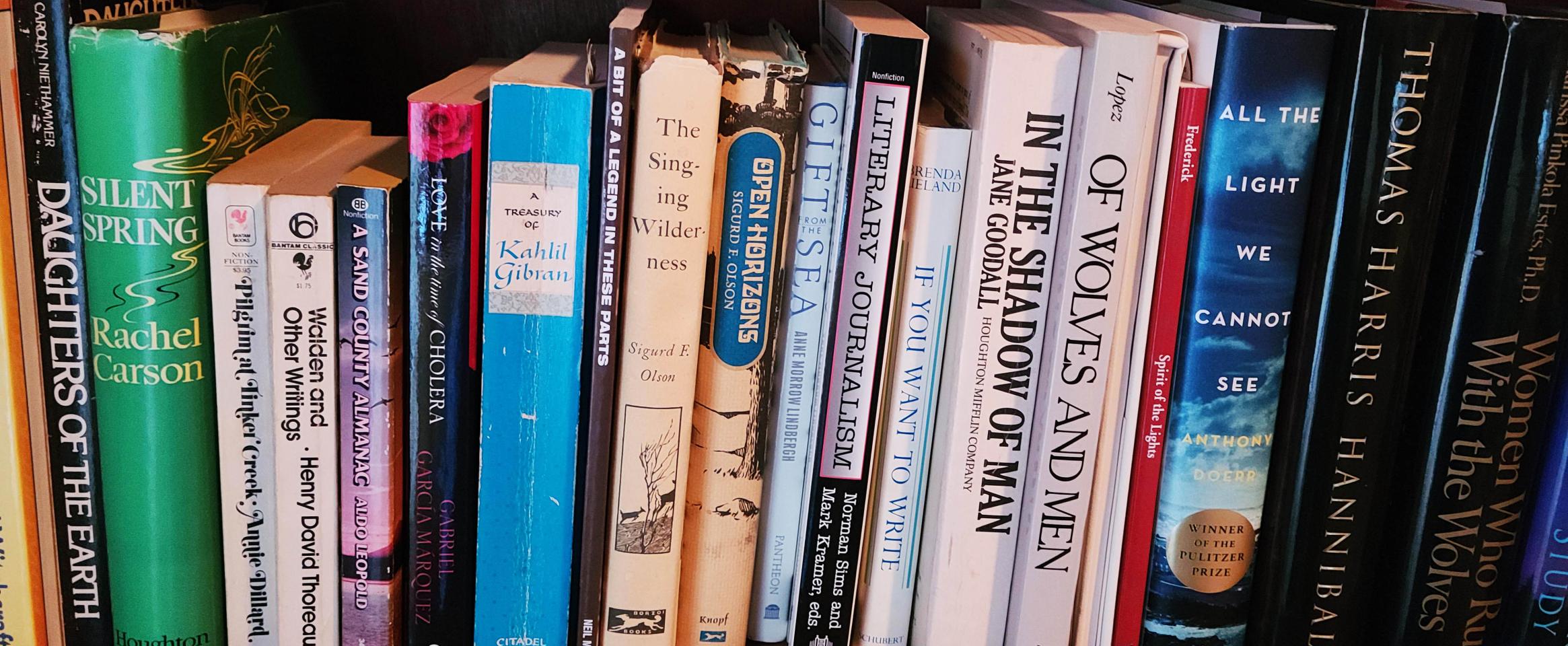 Rectangular photo of Marie Zhuikov’s office bookshelf with titles about wilderness and human nature. Photo credit Marie Zhuikov.