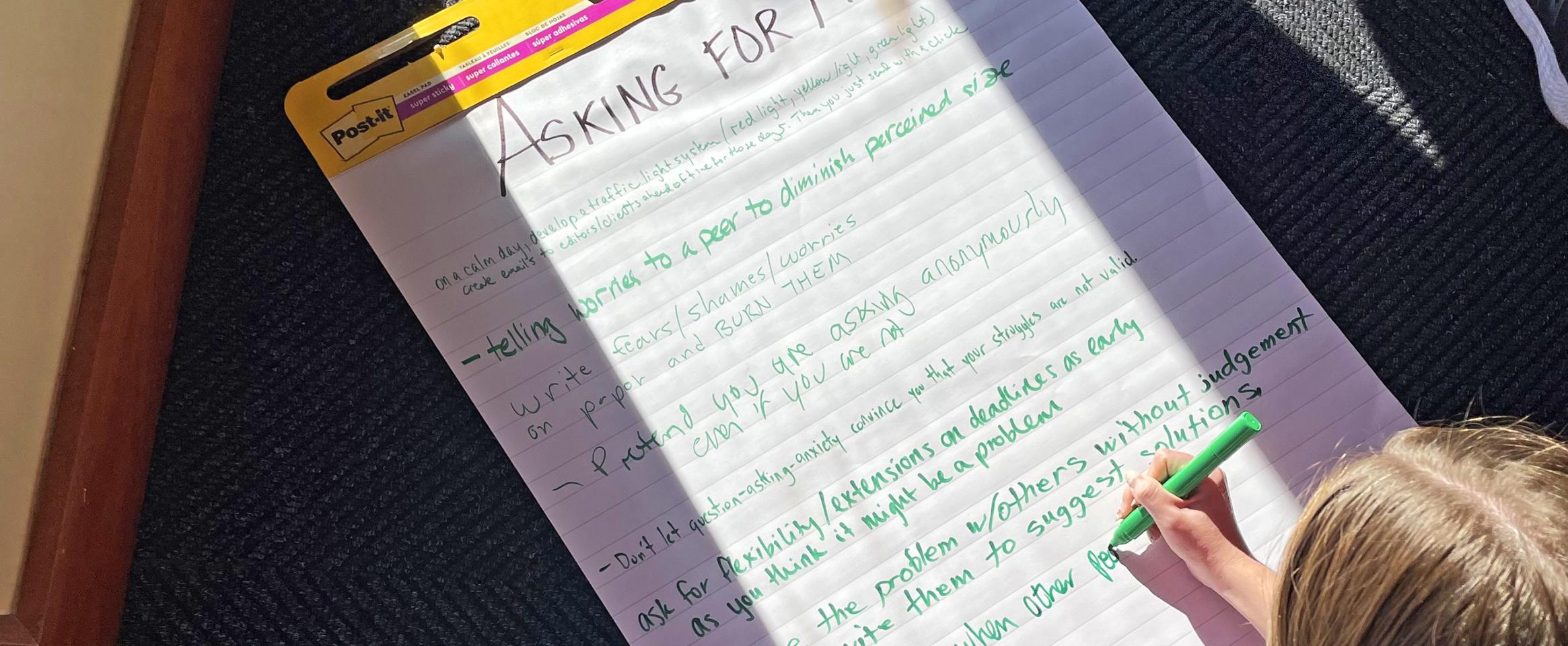 Attendee of hashtag Freelance Brain session filling out giant Post-it note during brainstorming activity, at the Touchdown Club at Folsom Field. Photo by Brent Foster.