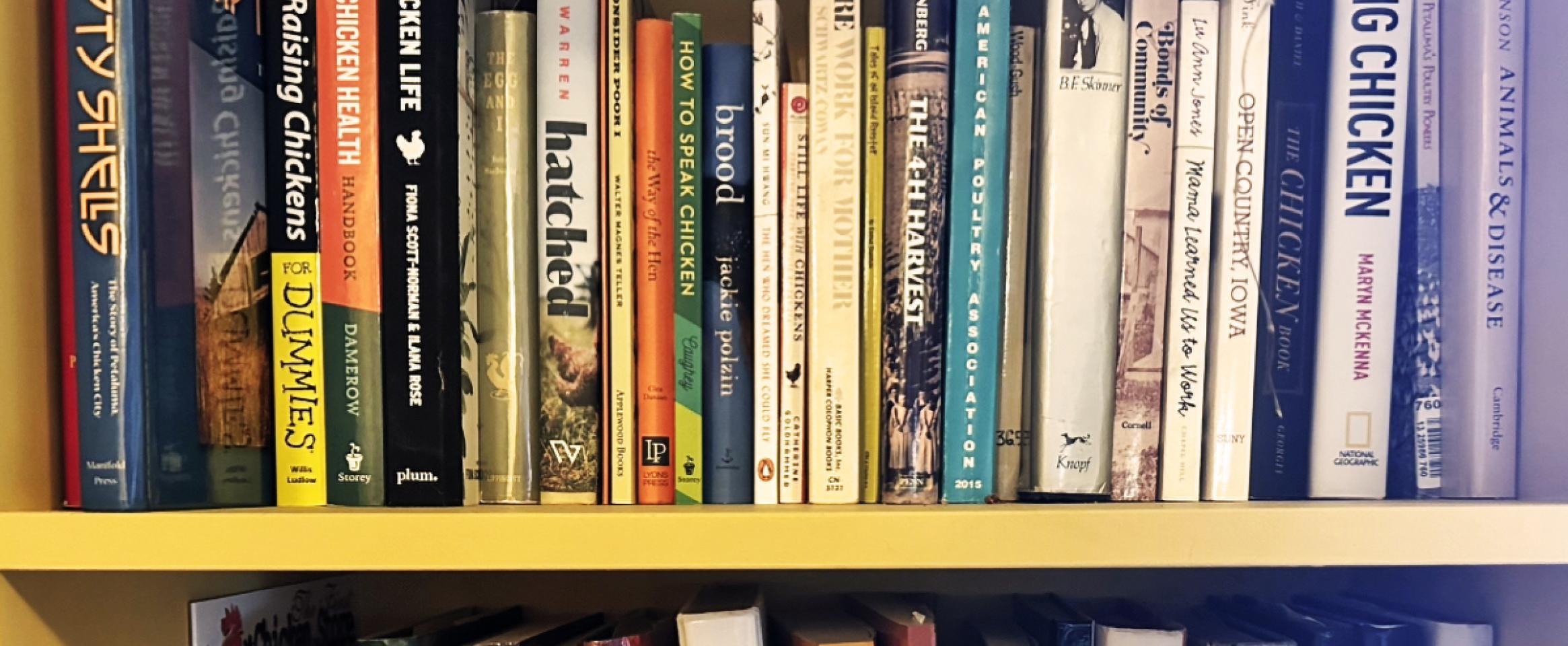 Rectangular photo of a close up view of books on a bookshelf, with spines facing out and many titles related to chickens.
