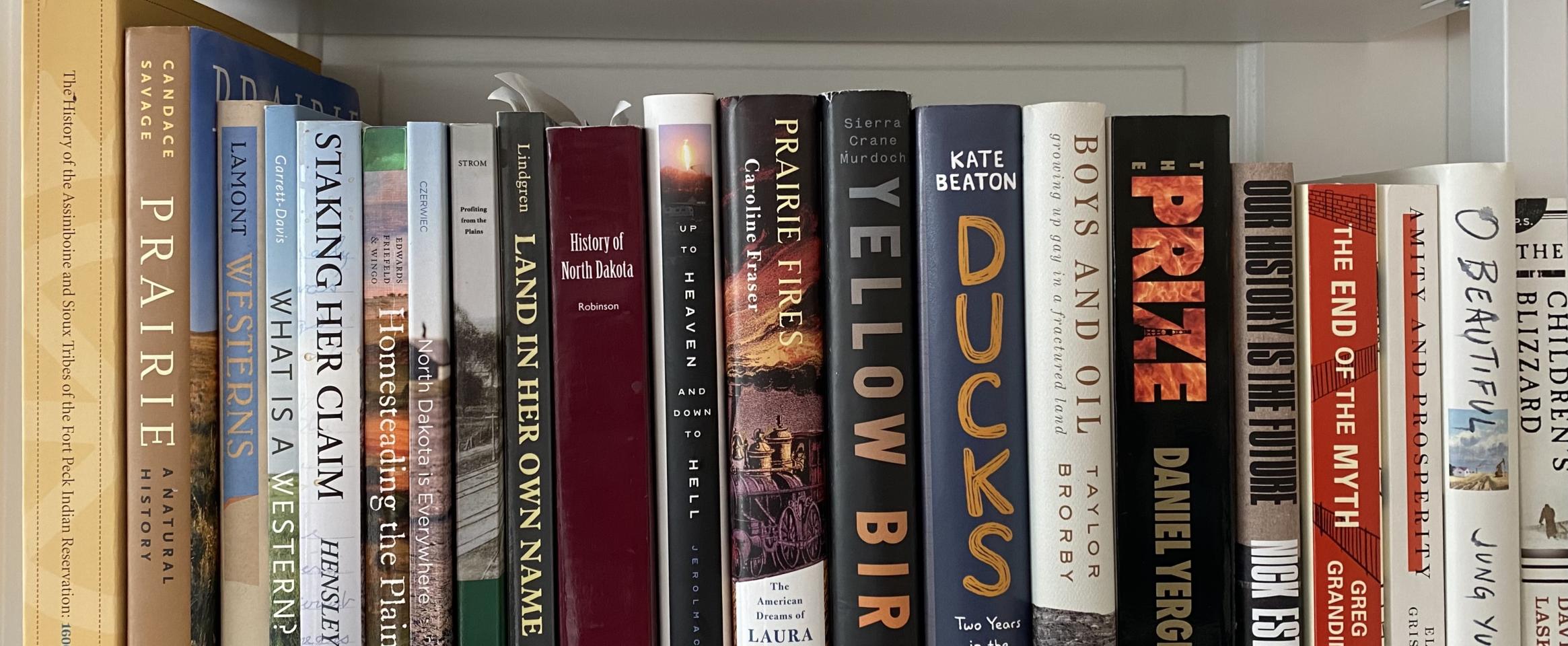 Rectangular photo of Erika Bolstad’s office bookshelf showing books on indigenous tribes, the history of North Dakota, prairie and western life, and oil exploration. Photo credit: Erika Bolstad 