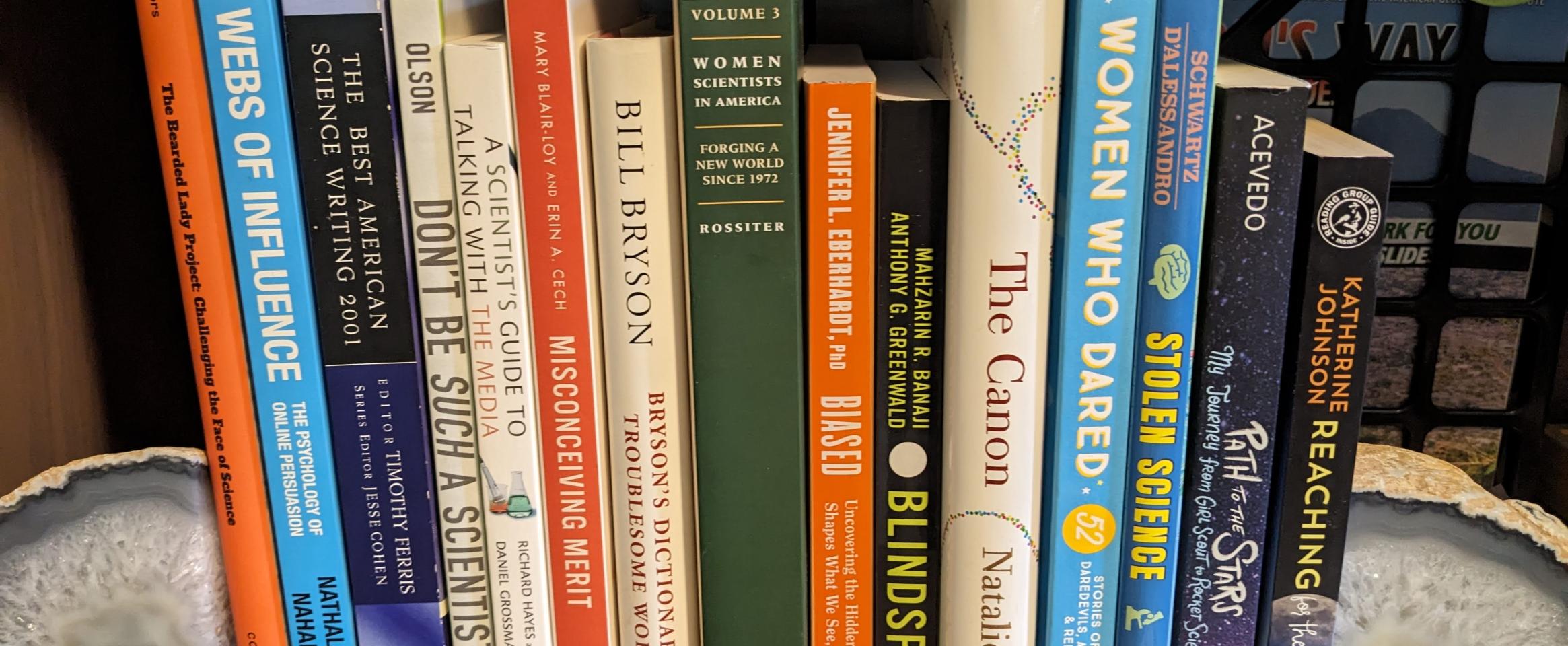 Rectangular photo of Lisa M. Pinsker Munoz’s office bookshelf showing books about and by women in science and challenges they faced in progressing in their careers. Photo credit Lisa M. Pinsker Munoz. 