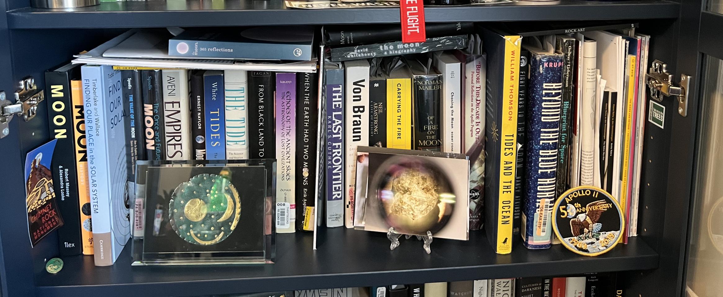 Rectangular photo of Rebecca Boyle’s office bookshelves showing works on the moon, the Solar System, tides, cosmology, and astronomy. Photo credit: Rebecca Boyle.