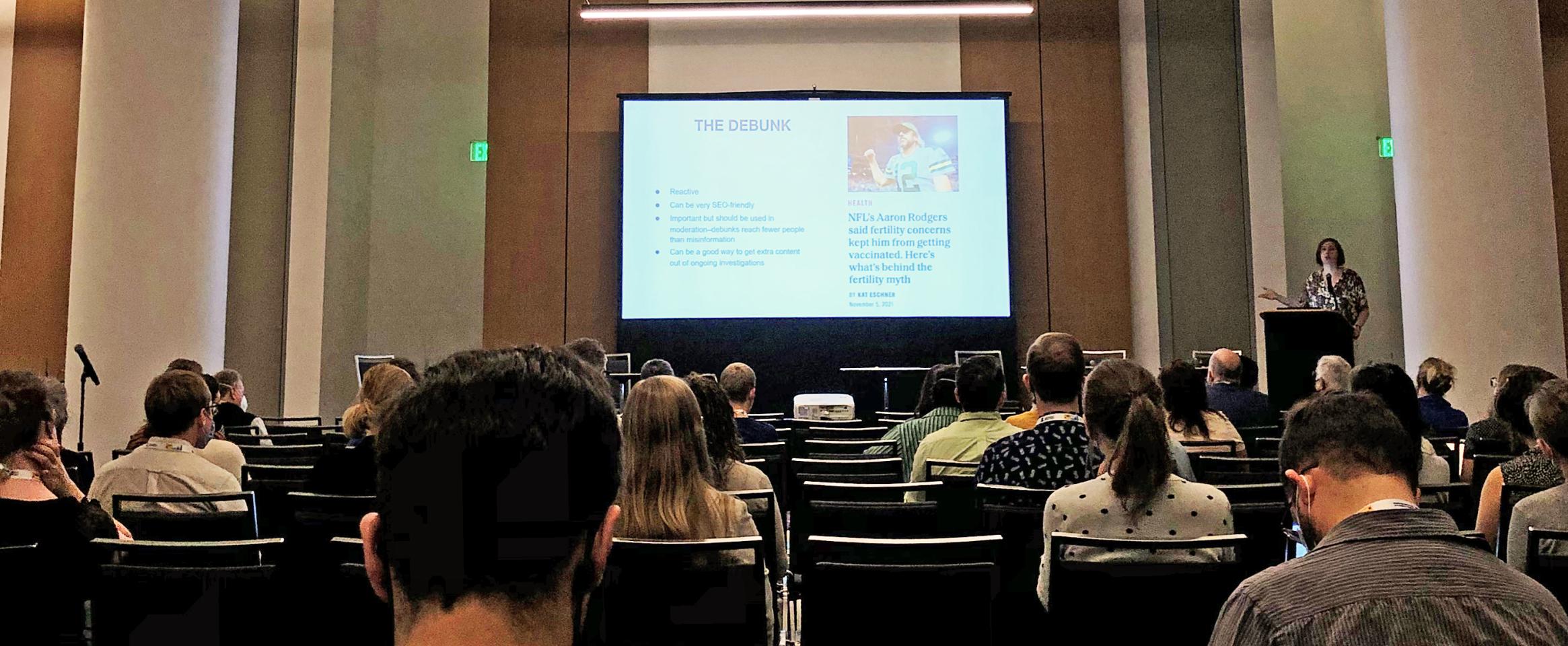 Photo of a conference room with screen in distance reading the Debunk and a photo of American football star Aaron Rodgers, taken at Science Writers 2022. Image by Ben Young Landis