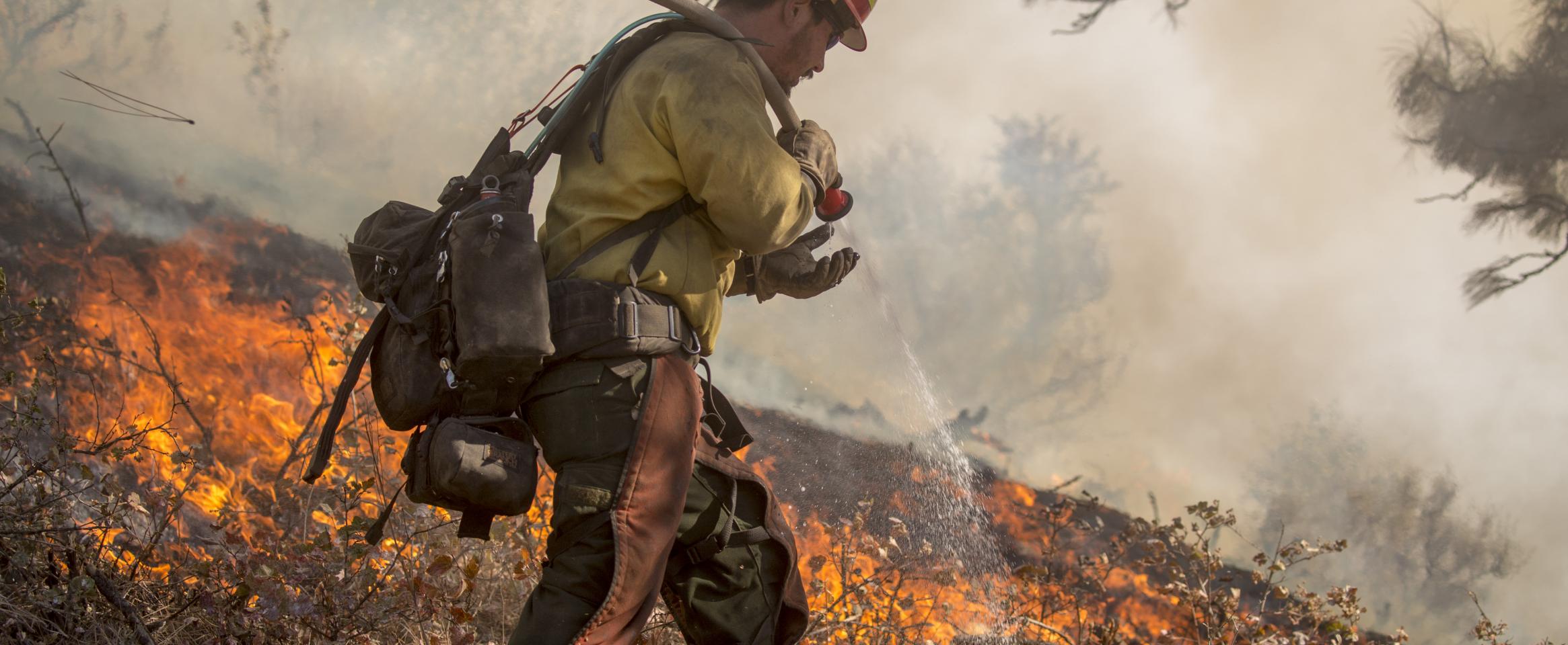 An Idaho firefighter douses flames in the Boise National Forest