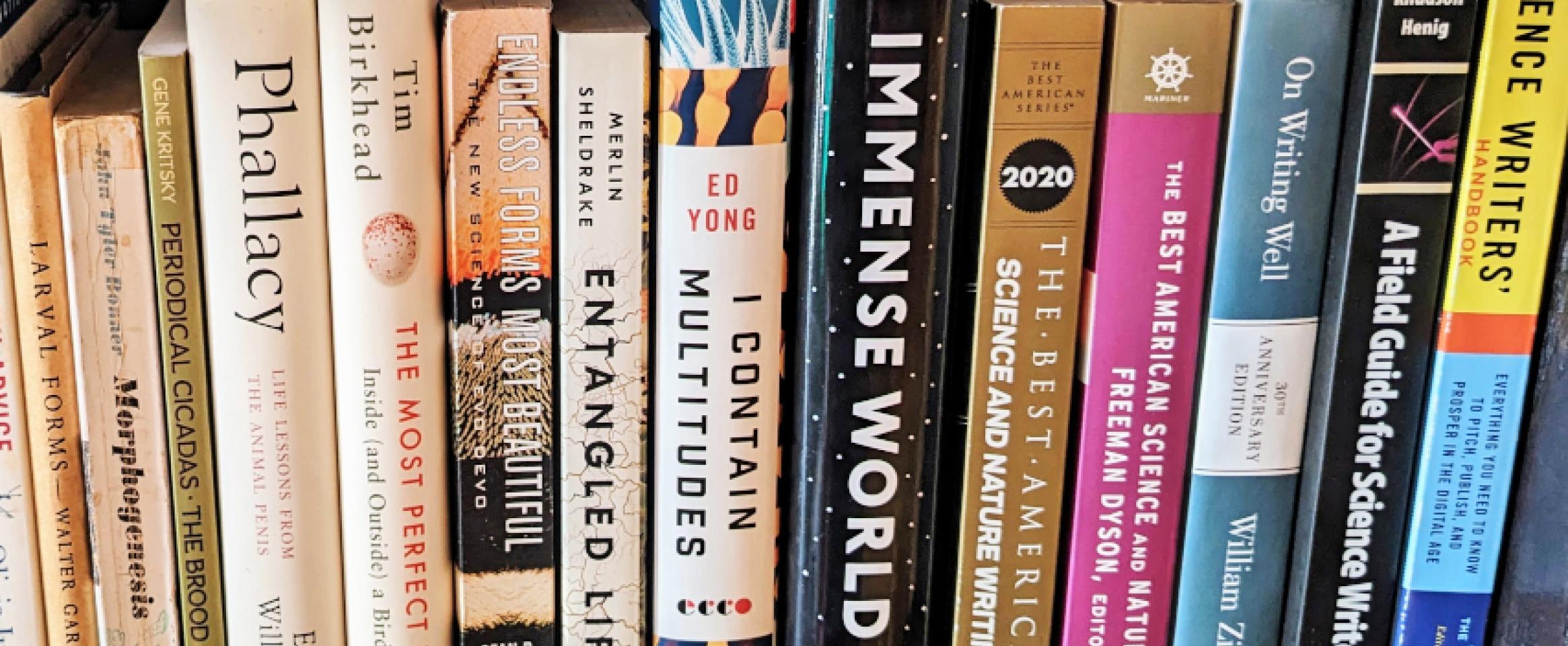 Rectangular photo of a closeup of books on a shelf, spanning titles on science writing. Photo by Danna Staaf