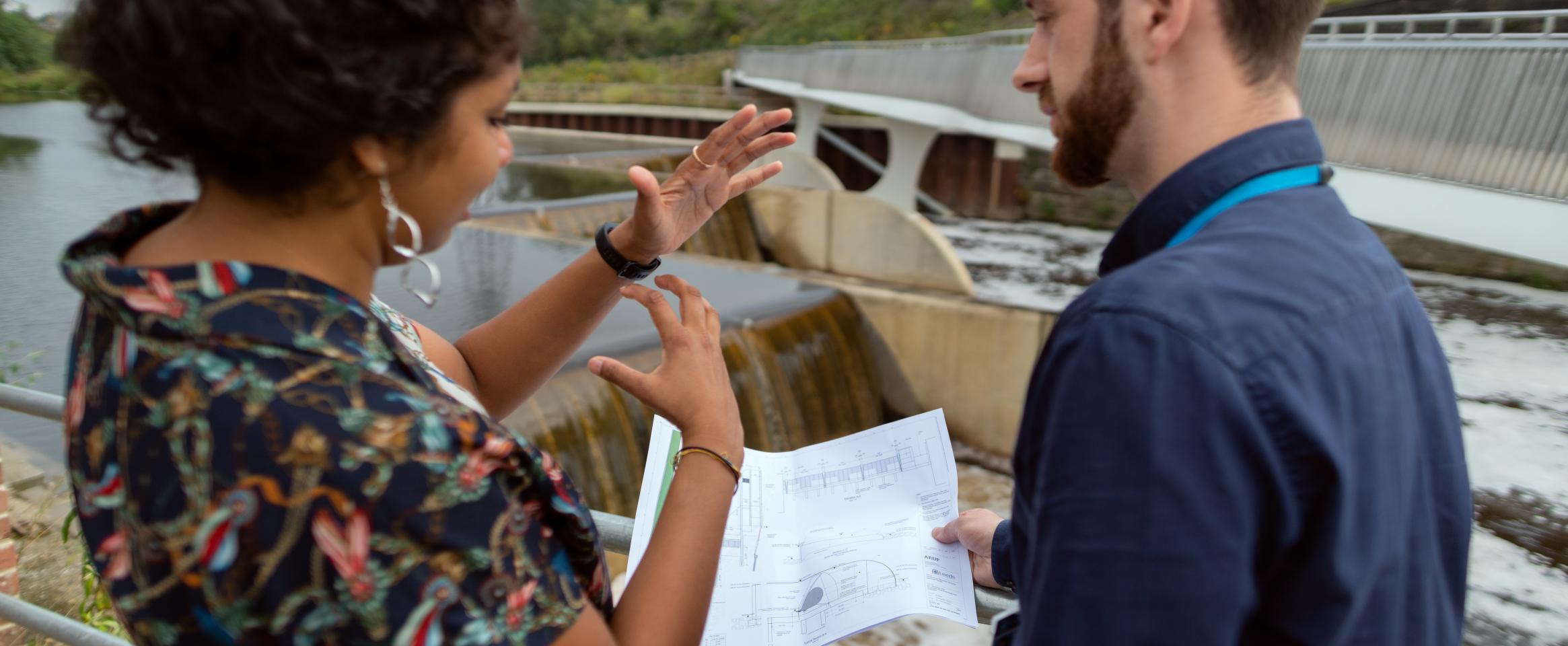 Civil engineer discusses weir plans with colleague