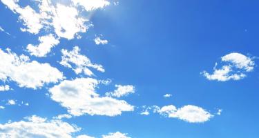 Horizontal photo of delicate white clouds scattered across a clear, sunny sky. Photo by Ashley Atkinson.