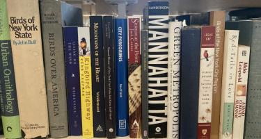 Rectangular photo of Ryan Goldberg’s office bookshelf showing books on urban ornithology, birds in America, birds in New York State, and specific species of birds. Photo credit: Ryan Goldberg 