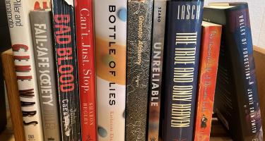 Rectangular photo of Charles Piller’s office bookshelf showing works on topics that include Alzheimer’s Disease, the Theranos scandal, unsafe manufacturing of generic medications, bias and fraud in medical research, and gene splicing, along with one of Piller’s own previous books, The Fail-Safe Society. Photo credit: Charles Piller.