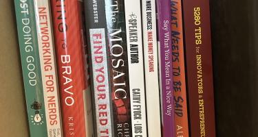 Rectangular photo of Alaina G. Levine’s office bookshelf showing works on public speaking, crisis management, sales, tips for entrepreneurs, and the author’s own book, Networking for Nerds. Photo credit: Alaina G. Levine.