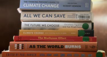 Rectangular photo of Meera Subramanian’s office bookshelf showing books on climate science, climate change, and climate change denial. Photo credit: Meera Subramanian.