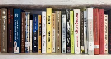 Rectangular photo of Melody Glenn’s office bookshelf showing works addressing such topics as the politics of overdose, drug addicts as patients, addicts who survived, undoing drugs, addiction and women, and opium. Photo credit: Melody Glenn.