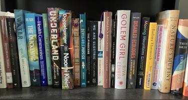 Rectangular photo of Lorraine Boissoneault’s office bookshelf showing works on disabilities, living with chronic illness, immunity, empathy, catastrophes, and works of poetry. Photo credit: Lorraine Boissoneault.