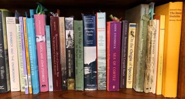Horizontal photo of a bookshelf of Liz Lee Heinecke, featuring titles on conservation, ecology, and evolution. Photo by Liz Lee Heinecke