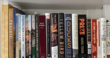 Rectangular photo of Erika Bolstad’s office bookshelf showing books on indigenous tribes, the history of North Dakota, prairie and western life, and oil exploration. Photo credit: Erika Bolstad