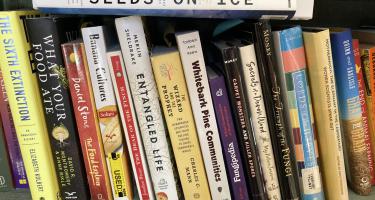 Rectangular photo of Emily Monosson’s office bookshelf showing titles on fungi and natural history. Photo credit Emily Monosson.
