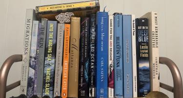 Rectangular photo of Karen Pinchin’s office bookshelf showing books on ocean life and fishing in general and bluefin tuna in particular. Photo credit Karen Pinchin.