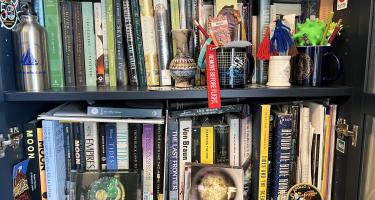 Rectangular photo of Rebecca Boyle’s office bookshelves showing works on the moon, the Solar System, tides, cosmology, and astronomy. Photo credit: Rebecca Boyle.