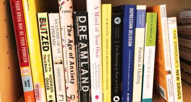 Rectangular photo of Ann Bracken’s office bookshelf showing titles on depression, anxiety, the opioid crisis, and psychoactive medications. Photo credit Ann Bracken.