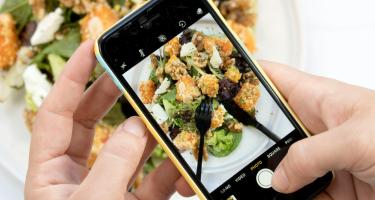 Closeup of a smartphone user's hands taking a photo of a meal. 