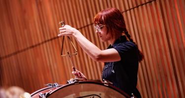 Percussionist in an orchestra playing a triangle.