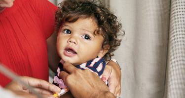 A toddler receives a vaccination in his arm.