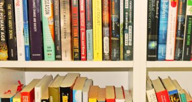 Horizontal photo of a bookshelf with four compartments visible, each filled with books