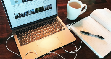Stock photo of open laptop next to coffee cup