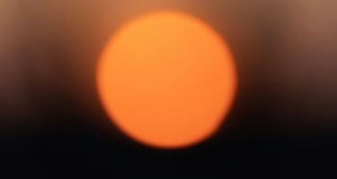 A hot orange sun against a dark background