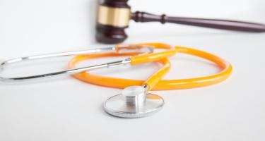 A stethoscope in front of a gavel.