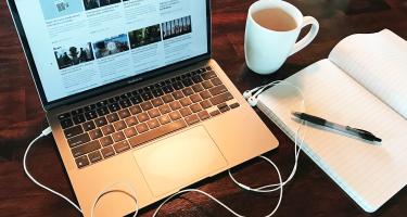 Srock photo of open laptop next to coffee cup