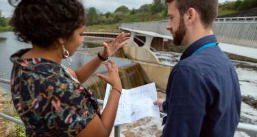 Civil engineer discusses weir plans with colleague