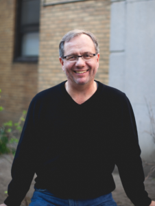 Portrait photo of Paul Raeburn wearing glasses, smiling