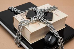 Chain and padlock on book and laptop