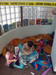 Children sitting in a reading nook with books.