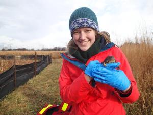 Rochelle Stiles standing in a field holding a frog.