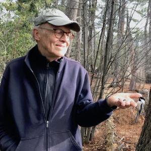Informal photo of David Stipp outdoors holding an earthworm in his hand to tempt a hungry bird.