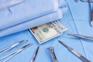 Cash and medical instruments image via Shutterstock