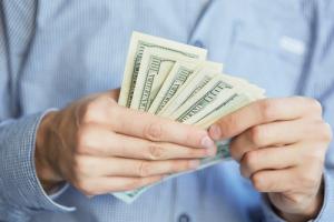 Man handling cash image via Shutterstock