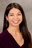 Portrait photo of Jill Sakai, with long hair and a studio backdrop