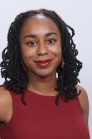 Vertical headshot photo of Talis Shelbourne with natural hair in twists and studio backdrop