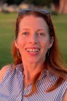 Vertical headshot photo of Aryn Baker, with shoulder length hair and grassy field background